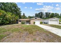 Tan brick ranch home with a two-car garage and a spacious lawn at 5393 68Th N St, St Petersburg, FL 33709