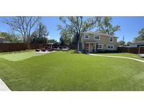 A sprawling green backyard featuring a putting green, deck with outdoor furniture, and a two-story home in the background at 4438 58Th N Ave, St Petersburg, FL 33714