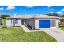 Single-Gathering home with gray exterior, blue garage door, and landscaped yard at 11247 Corey Pavin Ln, San Antonio, FL 33576