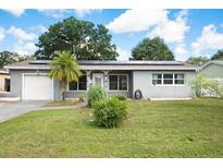 Gray house with solar panels, white garage door, and landscaped lawn at 5575 6Th N Ave, St Petersburg, FL 33710