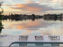 Beautiful waterfront view at sunset with seating, showcasing a serene and picturesque setting at 440 64Th Ave, St Pete Beach, FL 33706