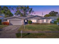 Gray house with white garage door, landscaping, and a well-maintained lawn at 13923 Wildwood Dr, Largo, FL 33774