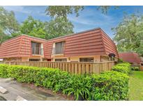 Townhouse with red tile roof, fenced yard, and lush landscaping at 707 1St Ct, Palm Harbor, FL 34684