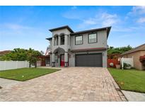 Contemporary two-story home featuring a brick driveway, two-car garage, and decorative columns under a blue sky at 6016 82Nd N Ter, Pinellas Park, FL 33781
