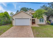 Two-story home with a white garage door and brick driveway at 1950 Lillian Ave, Tarpon Springs, FL 34689