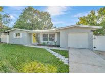 Charming ranch home with a yellow door and well-maintained lawn at 10617 N 27Th St, Tampa, FL 33612