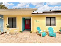 Inviting exterior with teal chairs and a red door at 102 Anclote Rd, Tarpon Springs, FL 34689