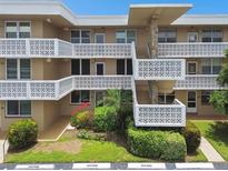 Tan condo building with block white railings, stairs, and neatly trimmed landscaping, and visitor parking at 5095 Bay Ne St # 114, St Petersburg, FL 33703