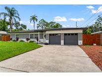 Modern home exterior with gray garage doors and a well-manicured lawn at 949 Lake Dr, Dunedin, FL 34698