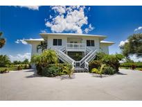 Two-story home with white exterior, large windows, and a spacious driveway at 13064 Via Flavia, Placida, FL 33946
