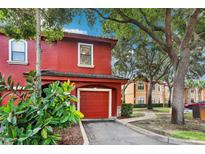 Red two-story townhome with attached garage and lush landscaping, located in a tree-lined community at 2272 Chianti Pl # 4-0048, Palm Harbor, FL 34683