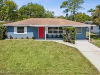 Newly renovated home with red door, blue exterior, and well-manicured lawn at 5425 Waters Edge Dr, New Port Richey, FL 34653