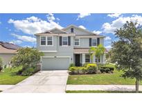 Two-story house with a light gray exterior, two-car garage, and landscaping at 31980 Goddard Dr, Wesley Chapel, FL 33543