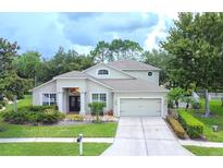 Two-story home with a three car garage and landscaping at 7323 Night Heron Dr, Land O Lakes, FL 34637