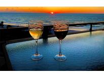Sunset view from a balcony with two glasses of wine, offering a serene and relaxing ambiance at 2618 Gulf Blvd # 505, Indian Rocks Beach, FL 33785