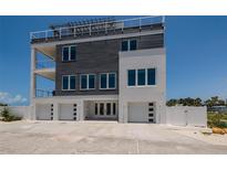 Modern three-story home showcasing a sleek design with a rooftop deck and an attached three-car garage at 2 4Th Ave, Indian Rocks Beach, FL 33785