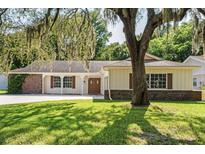 Charming home featuring well-manicured lawn, mature trees, and distinctive architectural details at 12912 Willoughby Ln, Hudson, FL 34667