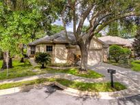 Tan house with a single-car garage and mature landscaping at 3570 Golfside Dr, Palm Harbor, FL 34685