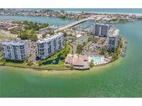 Aerial view of waterfront community with pool, tennis courts, and lush landscaping at 9415 Blind Pass Rd # 803, St Pete Beach, FL 33706