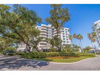 Luxury condo building with lush landscaping and palm trees at 1 Seaside Ln # 104, Belleair, FL 33756