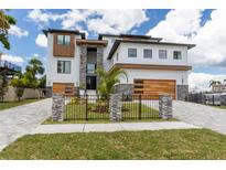 Modern home with stone accents, a fenced yard, a two-car garage, and meticulous landscaping on a sunny day at 2121 Bayou Grande Ne Blvd, St Petersburg, FL 33703