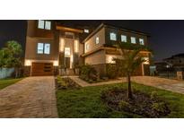 Stunning, modern home with stone accents, wood garage doors, manicured landscaping and welcoming exterior lighting at 2121 Bayou Grande Ne Blvd, St Petersburg, FL 33703
