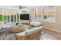 Bright living room featuring a ceiling fan, tile floors, a woven coffee table, and waterfront views at 100 Oakmont Ln # 301, Belleair, FL 33756
