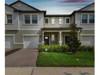 Charming townhome featuring a well-maintained lawn, brick driveway, and an inviting covered front porch at 21811 Lyonia Ln, Land O Lakes, FL 34637