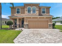Two-story house with tan exterior, stone accents, and paver driveway at 116 Caladium Ct, Bradenton, FL 34212