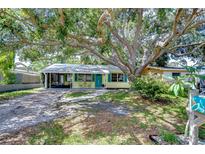 Charming single-story home featuring a bright exterior, mature trees, and a welcoming front porch with seating at 5210 Newton S Ave, Gulfport, FL 33707