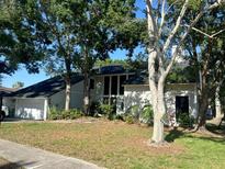 Charming two-story home boasts a dark roof, bright exterior paint, attached two car garage and mature landscaping at 5841 Bay Pines Lakes Blvd, St Petersburg, FL 33708