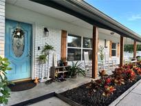 Charming front porch with brick facade, rocking chairs, and a vibrant blue front door at 7809 Alafia Dr, Riverview, FL 33578