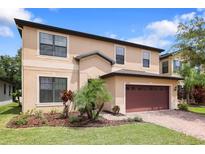Two-story house with a red garage door and landscaping at 15250 Anguilla Isle Ave, Tampa, FL 33647