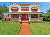 Two-story house with brick accents, a red door, and a well-manicured lawn at 1100 Beach Ne Dr, St Petersburg, FL 33701