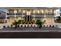 Two-story house with lighted staircase and landscaping at 83 Palm Blvd, Dunedin, FL 34698