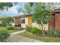 Brick building exterior with a walkway, landscaping, and grill at 845 Maclaren N Dr # D, Palm Harbor, FL 34684