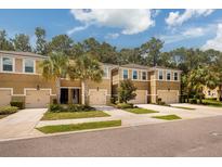 Three tan townhouses with garages and palm trees at 17860 Althea Blue Pl, Lutz, FL 33558