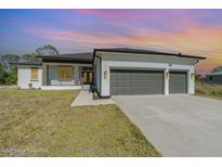 Charming exterior elevation of a modern home with a spacious three-car garage and stone accents at 14346 San Domingo Blvd, Port Charlotte, FL 33981