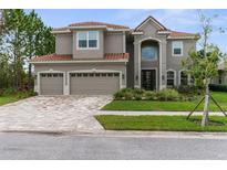 Stunning two-story home with red tile roof, three-car garage and brick-paved driveway at 32924 Estate Garden Dr, Wesley Chapel, FL 33545