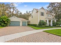 Charming two-story home with a two-car garage, lush landscaping, and brick driveway at 13929 Lake Fishhawk Dr, Lithia, FL 33547