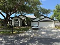 Charming single-story home with a well-manicured lawn, mature trees, and a three-car garage at 4749 Stoneview Cir, Oldsmar, FL 34677