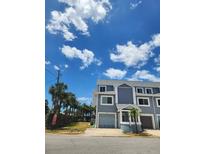 A light blue two-story townhouse with an attached garage on a sunny day at 900 Harbour House Dr, Indian Rocks Beach, FL 33785