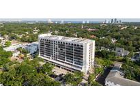 Stunning aerial view of a high-rise condominium building in a lush, green neighborhood near downtown with a water view in the distance at 3211 W Swann Ave # 808, Tampa, FL 33609