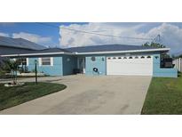 Charming blue one-story home with a well-manicured lawn and a spacious driveway leading to an attached two-car garage at 3510 Magnolia Way, Punta Gorda, FL 33950