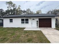 Newly renovated single story house with dark brown garage door at 15017 Omaha St, Hudson, FL 34667