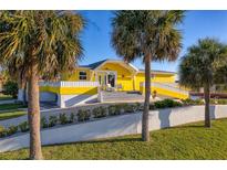 Bright yellow house with palm trees, showcasing a welcoming and spacious front yard at 4040 Hermosa Blvd, Hernando Beach, FL 34607