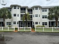 Two-story condo building with white exterior, screened balconies, and a white picket fence at 2077 Wetland Pt # 1202, Lutz, FL 33558
