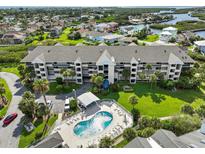 An aerial view showcasing a condo building, pool, and lush green space at 5537 Sea Forest Dr # 307, New Port Richey, FL 34652