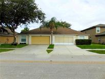 Charming duplex with well-maintained lawn, yellow garage doors, and lush landscaping, offering an inviting curb appeal at 9048 Southern Charm Cir, Brooksville, FL 34613