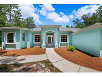 Single-story home with a light teal exterior and landscaped yard at 10463 Yellowlegs Ave, Weeki Wachee, FL 34614